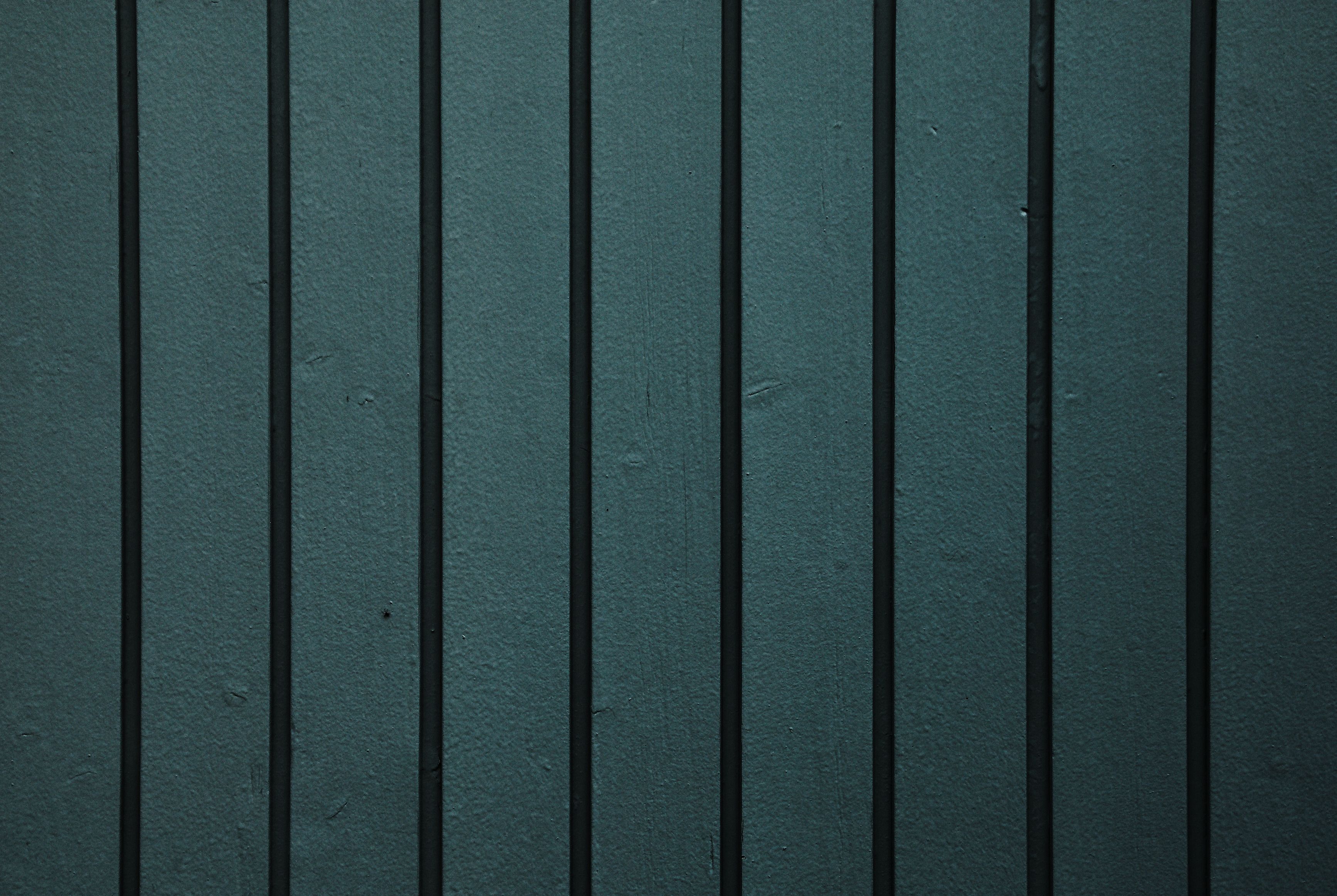 Close-up of dark wood-grain fence panels showing a finish similar to composite fencing